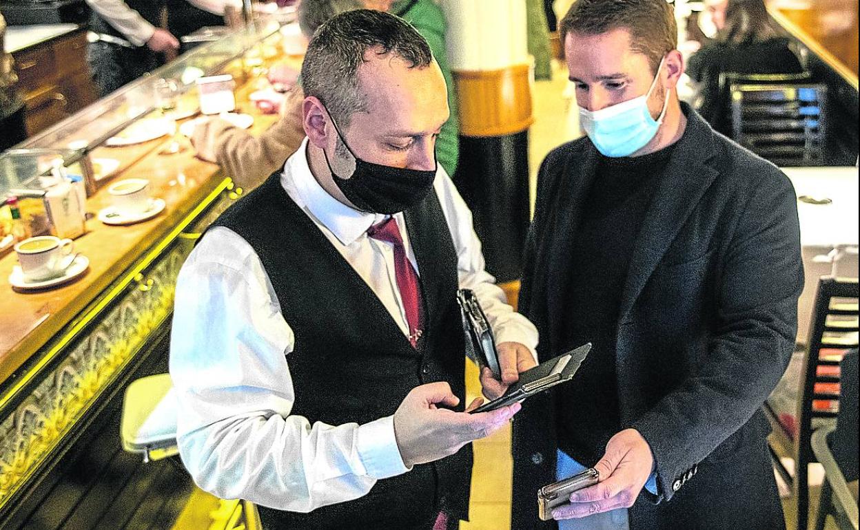 Un cliente muestra su pasaporte covid en un local de hostelería de Bilbao. 