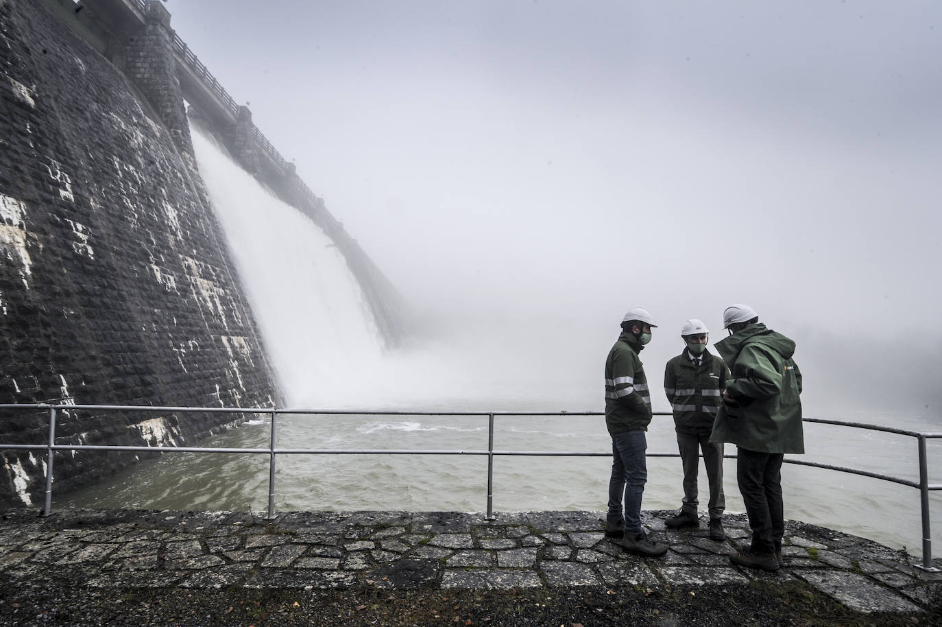 Francisco José López, jefe de Generación Hidráulica de la Cuenca Norte, José Antonio Villa, jefe de mantenimiento y operaciones, y Diego Ruiz, jefe del centro de producción, conversan bajo las compuertas del embalse.