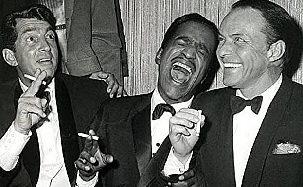 Imagen principal - Dean Martin junto a sus colegas del Rat Pack Sammy Davis Jr. y Frank Sinatra. En 'Río Bravo' con John Wayne y en una fotografía de 1980, con su eterno cigarrillo entre los dedos.