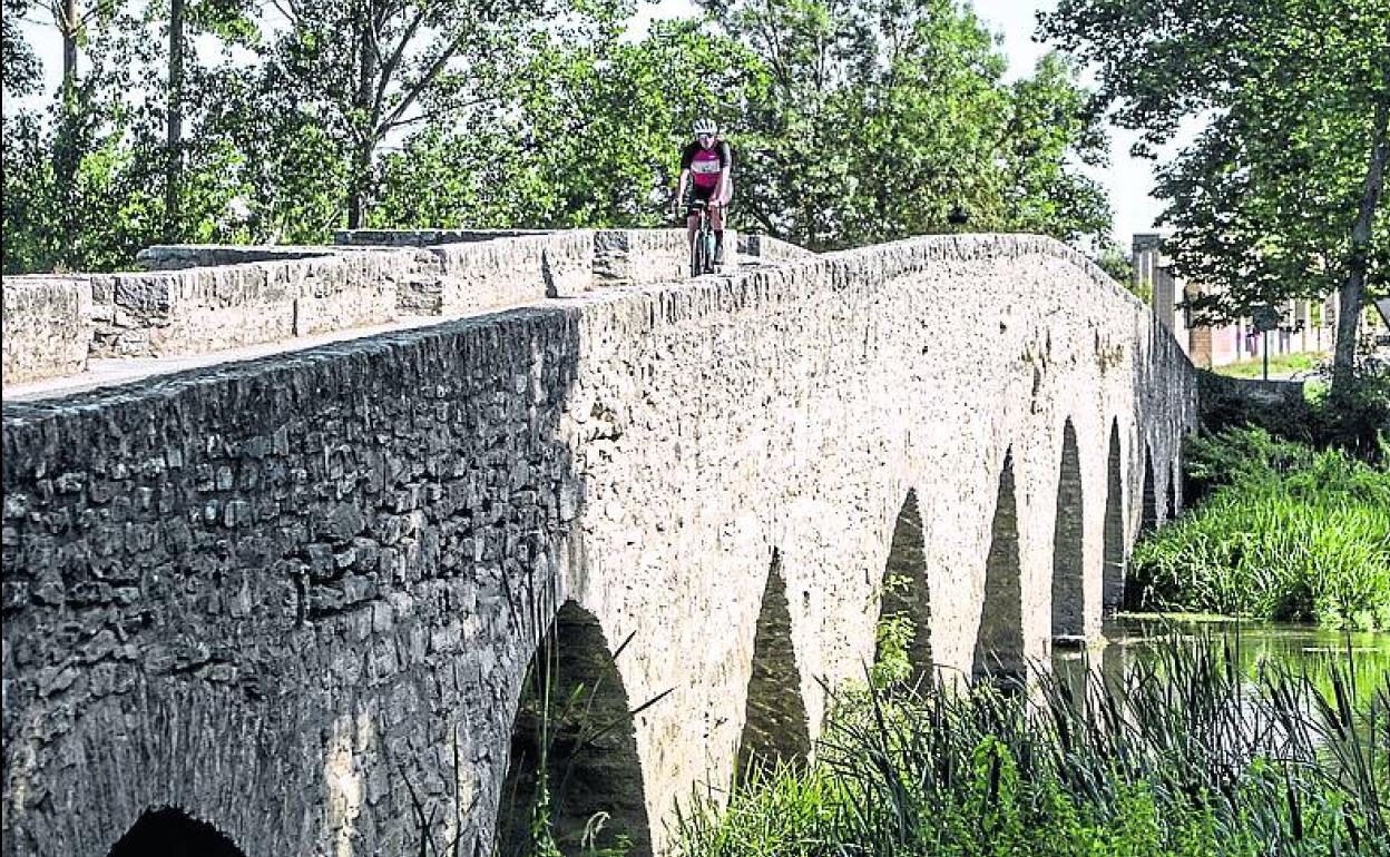 Un ciclista pasa por el puente de Víllodas. 