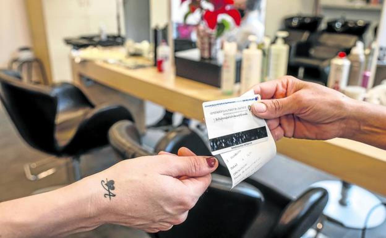 Una clienta de una peluquería en Vitoria recibe su ticket.