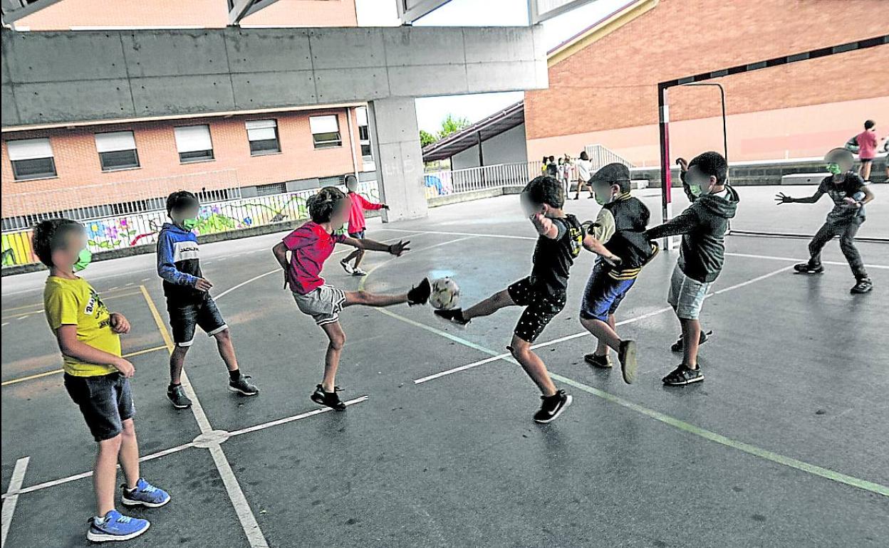 Un grupo de escolares juega a fútbol en el patio de un colegio. 