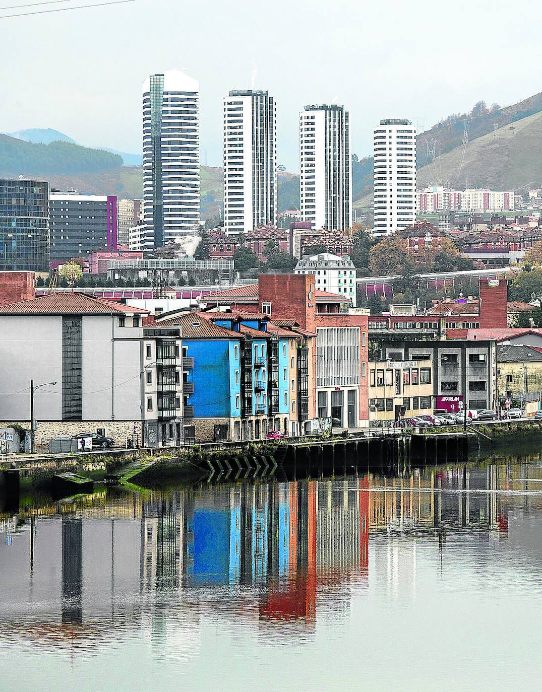 Edificios de la parte central de Zorrozaurre se reflejan en la ría con Bilbao al fondo. 