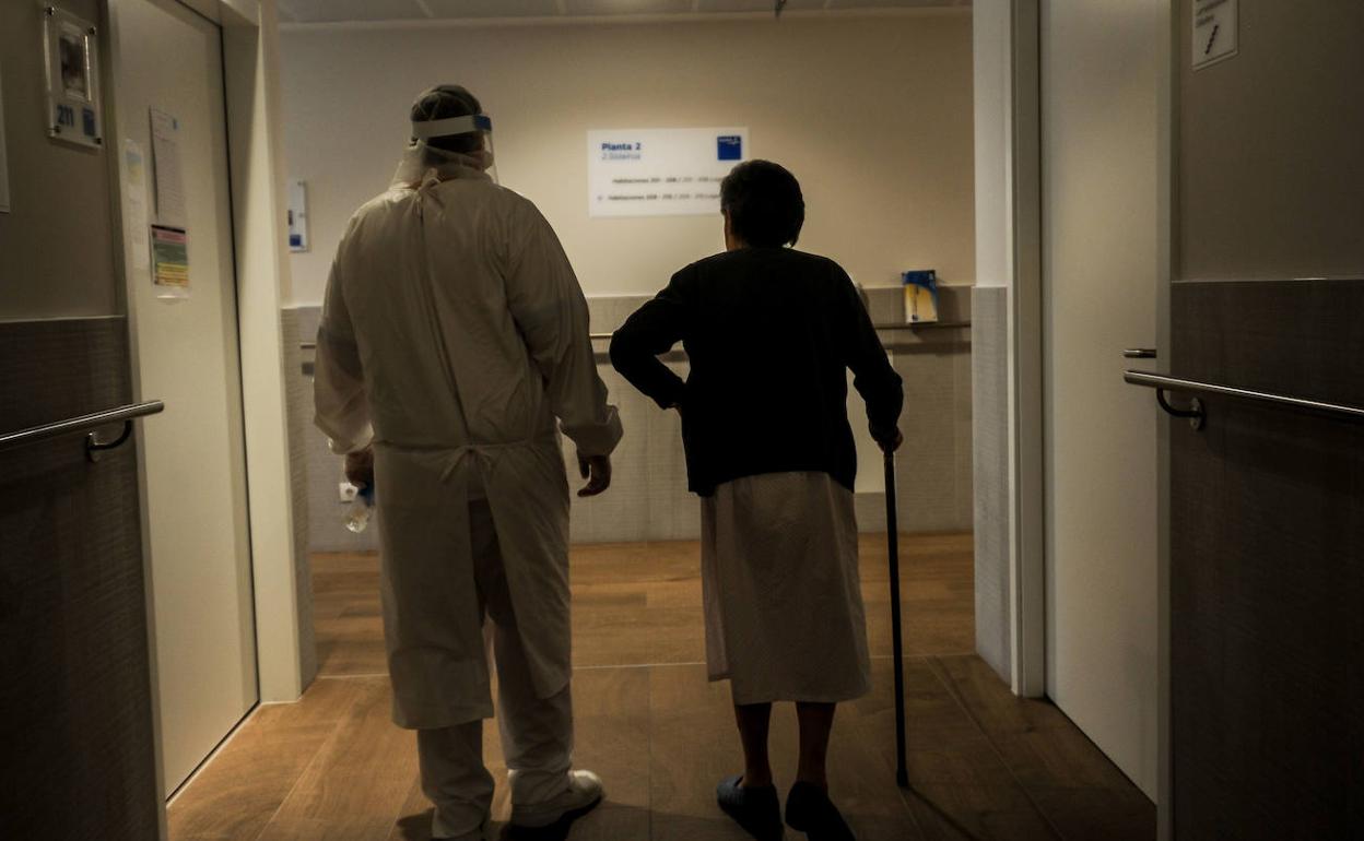 Un trabajador camina junto a una interna por los pasillos de una residencia.