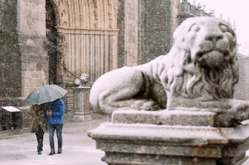 Dos personas se protegen de la nieve junto a los leones de la catedral de Ávila este miércoles. 