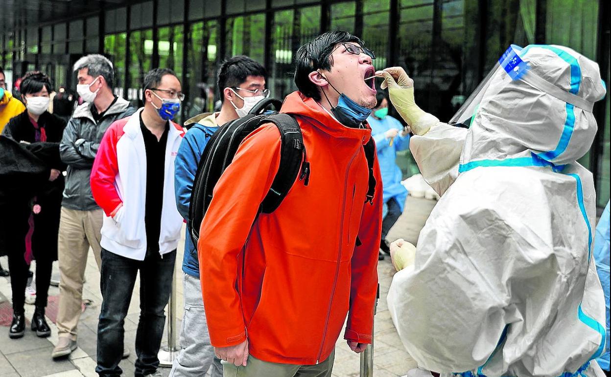 Cientos de personas hacen cola para someterse a las pruebas masivas de PCR debido al aumento de casos positivos de coronavirus en Pekín. 