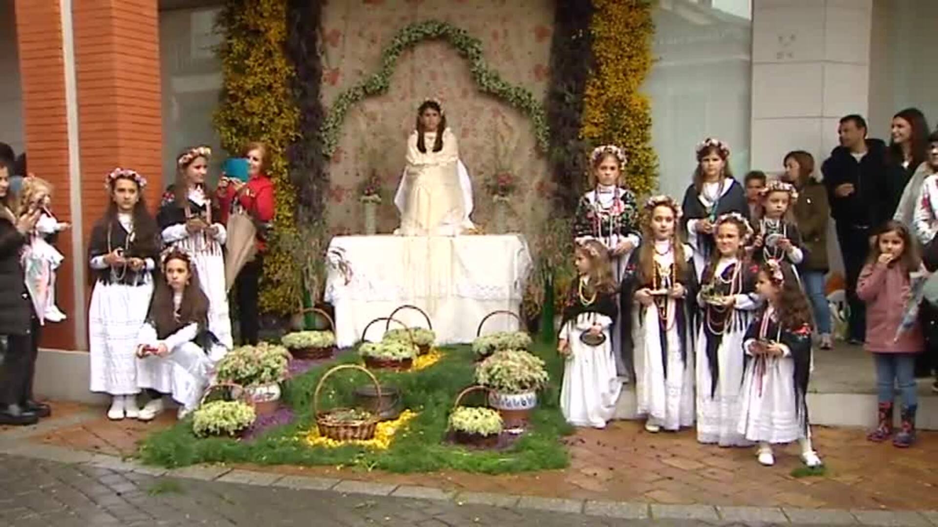 Niñas en un altar rodeadas de flores en la fiesta de La Maya de Colmenar  Viejo