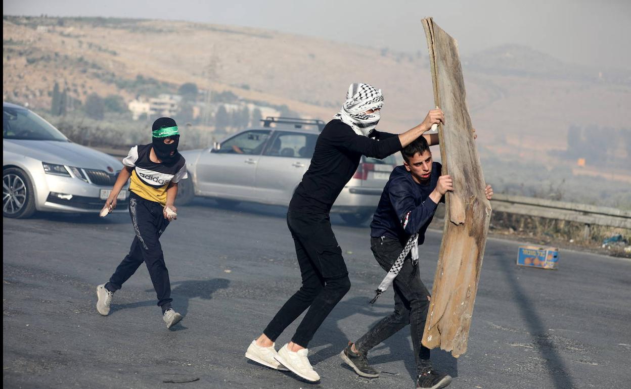 Varios civiles palestinos se enfrentan a las fuerzas israelíes cerca de Nablús protegiéndose con una plancha acartonada.