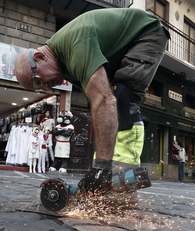Un operario sierra el punto de soldadura de una de las tapas situadas en el recorrido de los encierros que albergaran los postes sobre los que irán colocadas las tablas que conformaran el vallado en el tramo de Mercaderes.