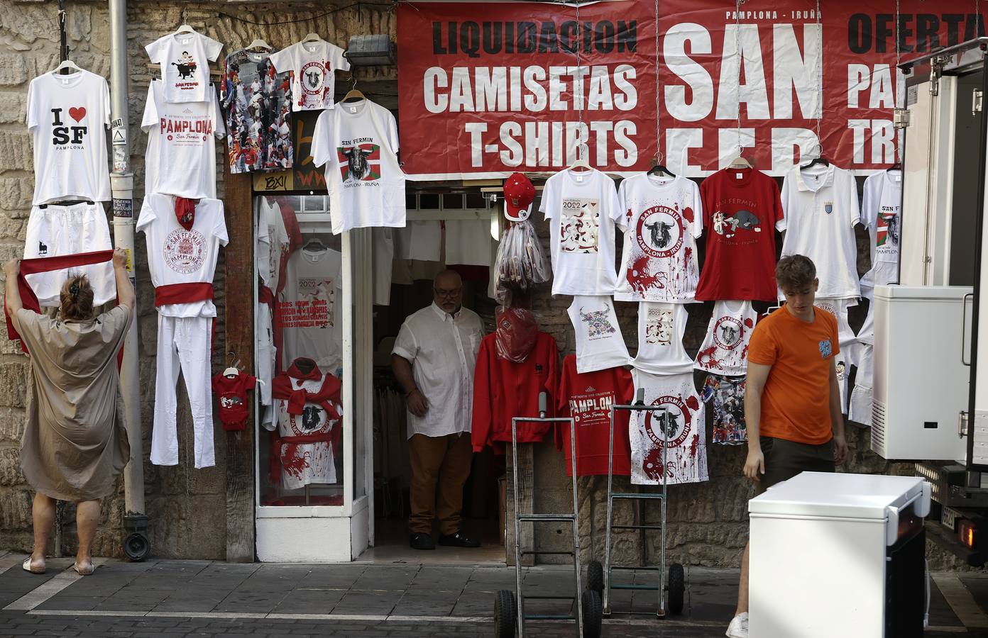 La dueña de un comercio del Casco Viejo de Pamplona coloca para su venta la ropa típica de los Sanfermines en la entrada a la tienda. 