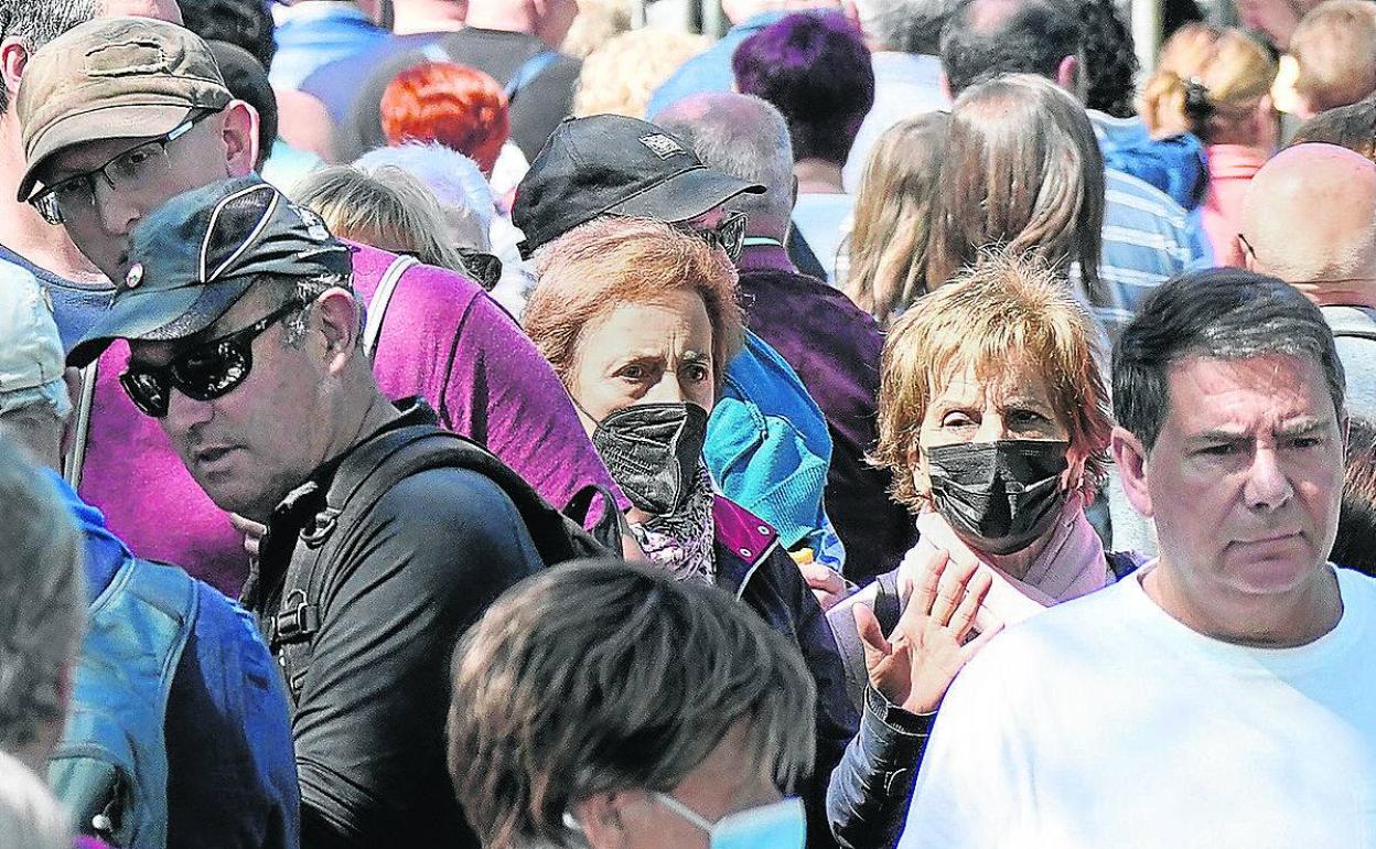 Personas mayores de 60 años con mascarilla en una aglomeración en la calle. 