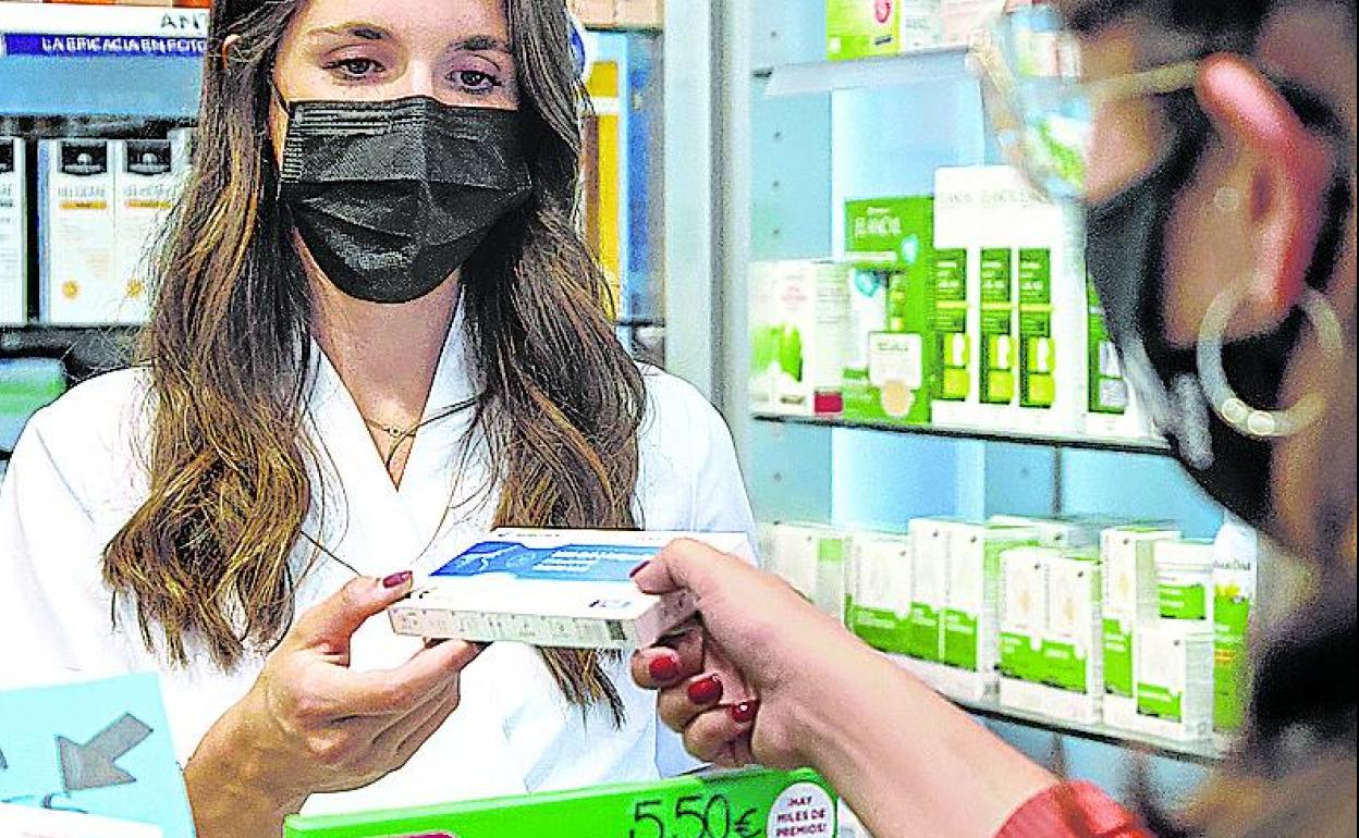 Una farmacéutica dispensa un test de antígenos a una clienta. 