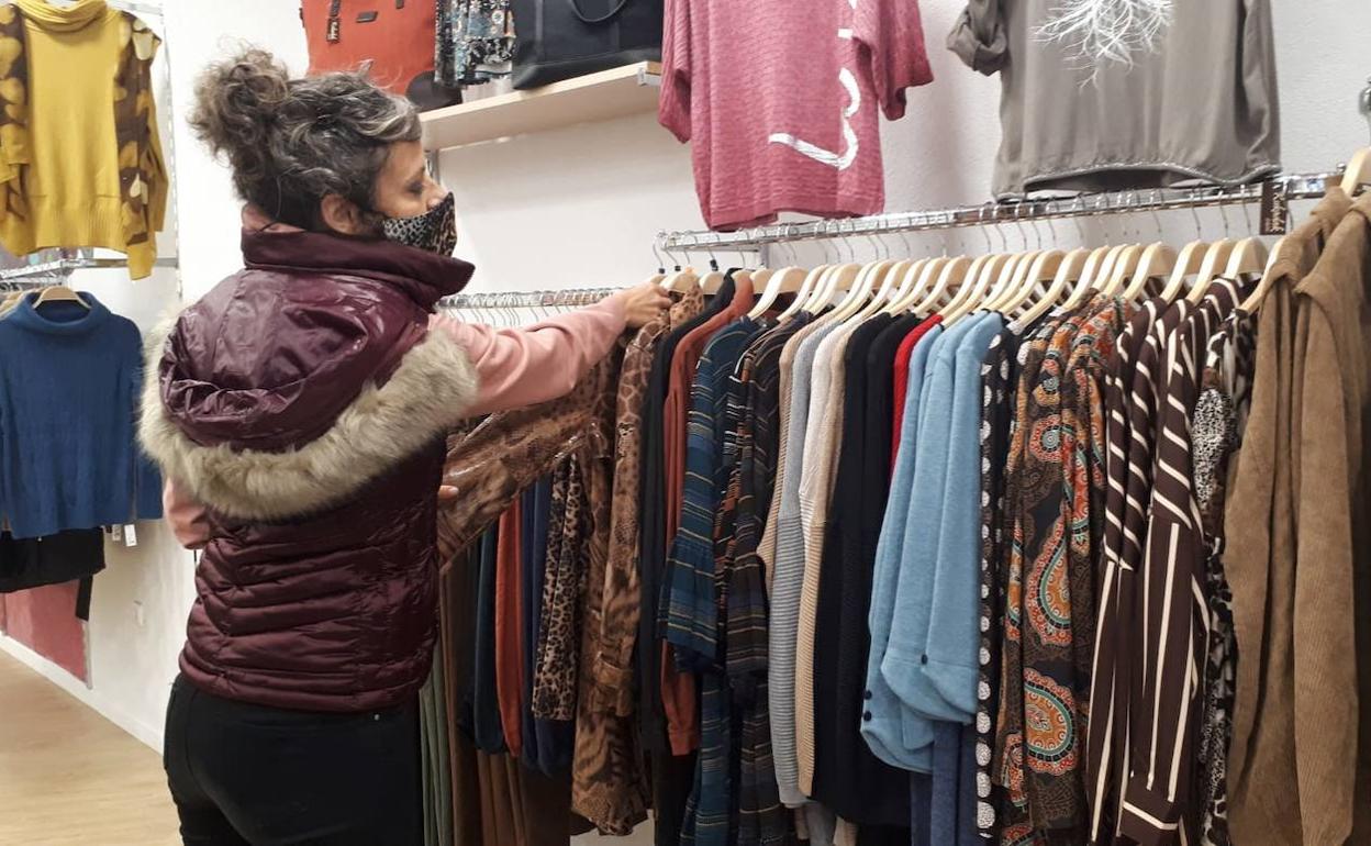 Una mujer ordena la ropa en una tienda de Lekeitio.