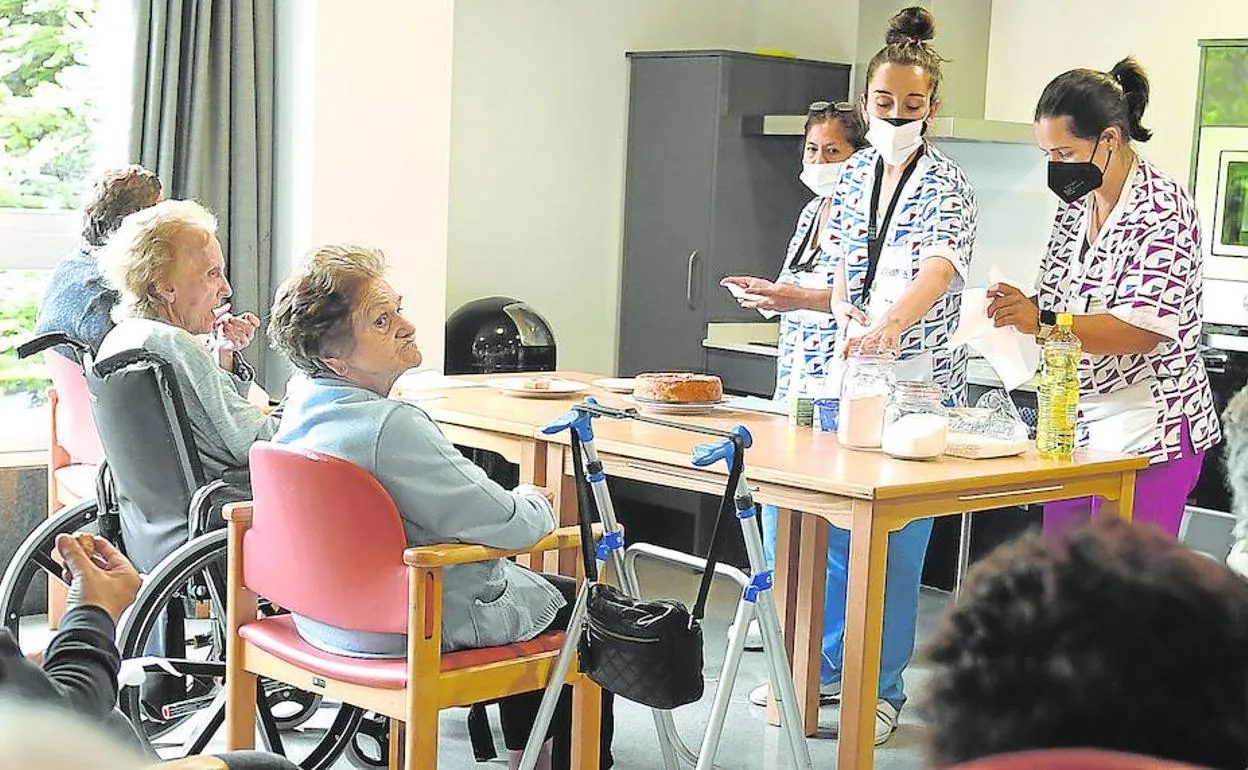 Tres profesionales de una de las unidades convivenciales de la residencia Loiu Gurena realizan una actividad de cocina con los usuarios. 