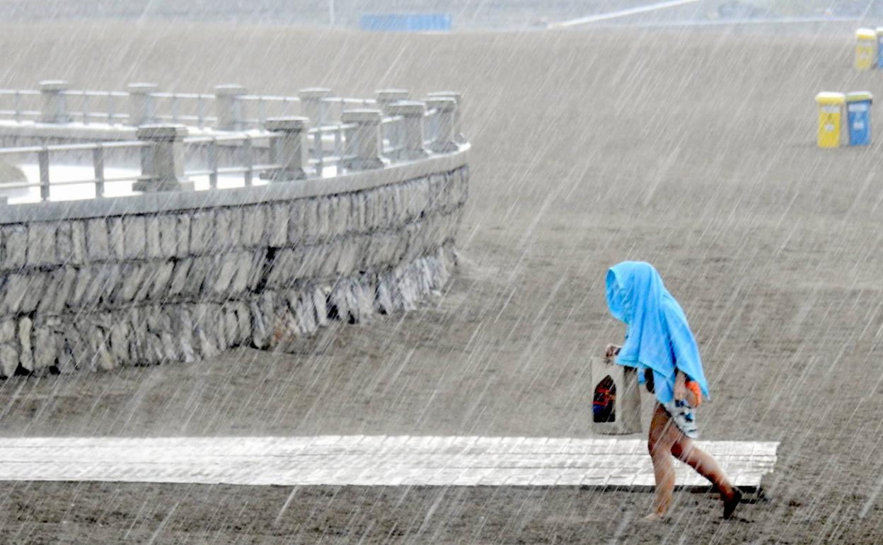 Una mujer corriendo tras entrar una galerna en la playa de Ereaga, Getxo.