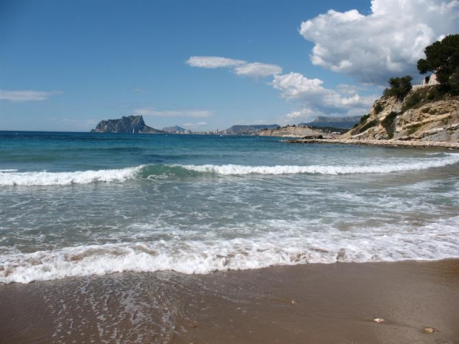 Playa del Portet, Moraira. Situada entre el puerto y la Torre de Vigilancia del Cap d'Or es perfecta para disfrutar del mar y del sol con total tranquilidad. Después de un día de playa, podrás refrescarte con una fría bebida en alguno de los bares de sus alrededores.