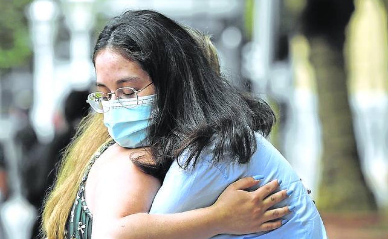 Raluca y Elisabeth se abrazan en un parque de Bilbao. Arriba a la derecha, detalle del parte médico donde los facultativos reconocen que las jóvenes sufrieron una «intoxicación». 