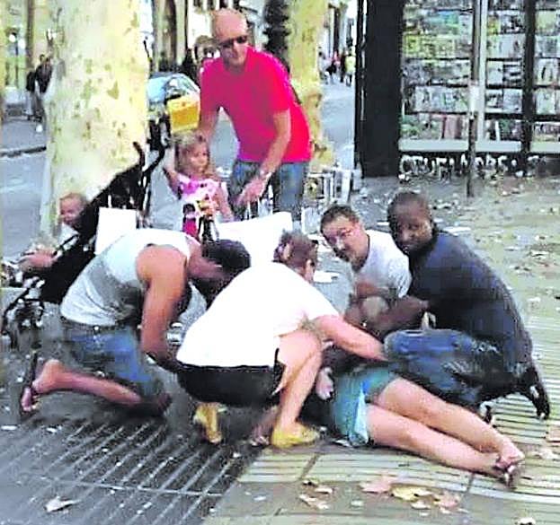 Varios transeuntes atienden a una de las personas arrolladas. 