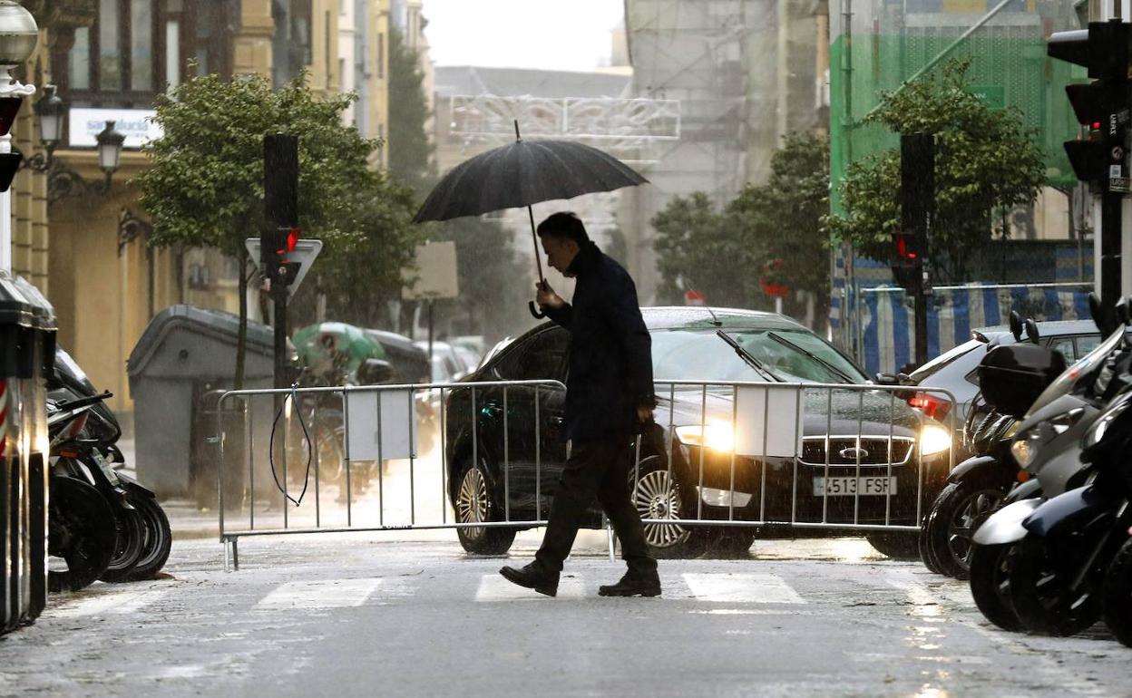 Un hombre se protege con un paraguas de una tormenta. 