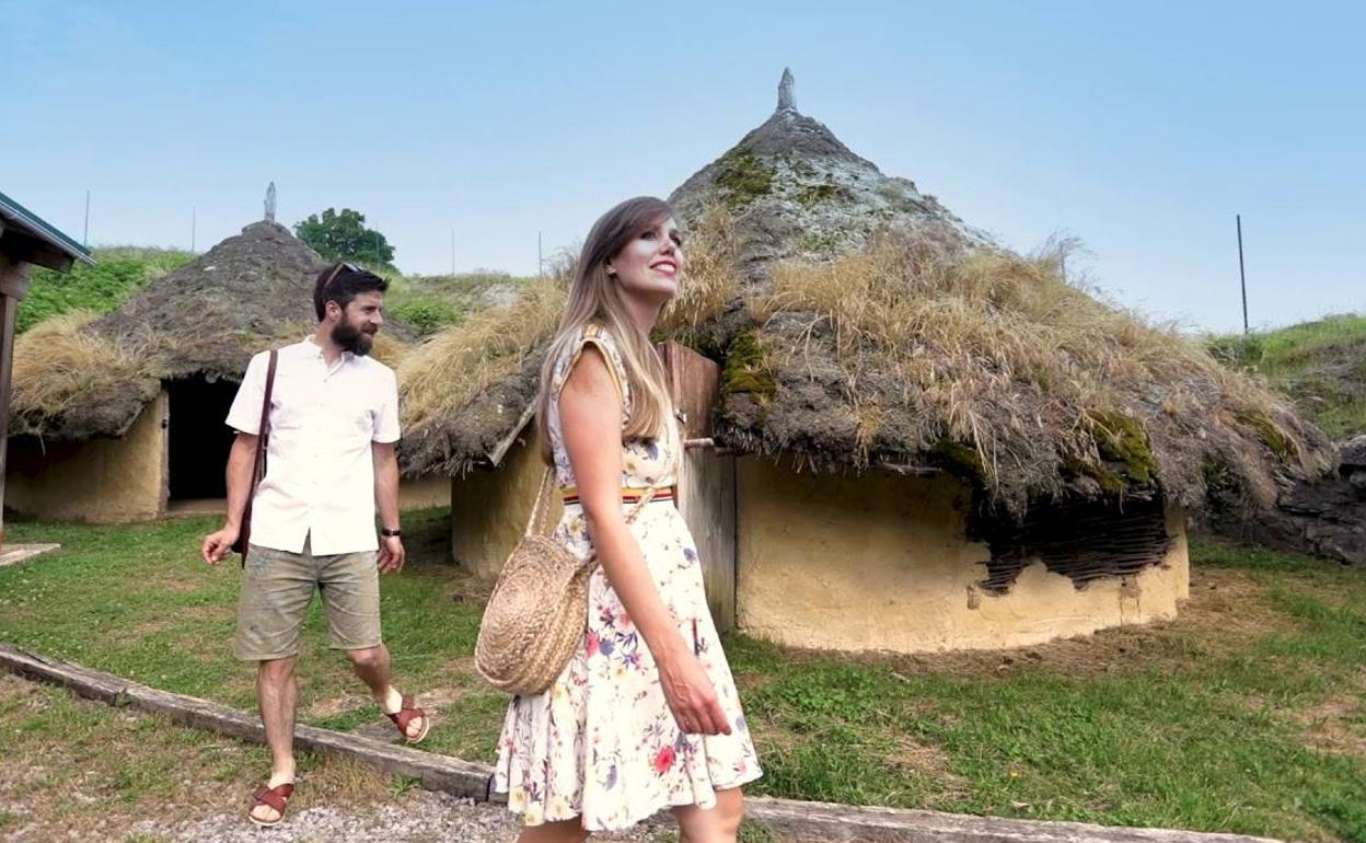 Una pareja recorre las cabañas reconstruidas del castro.
