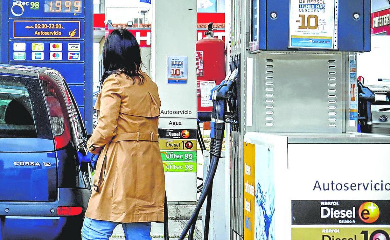 Una conductora reposta su vehículo en una estación de servicio. 