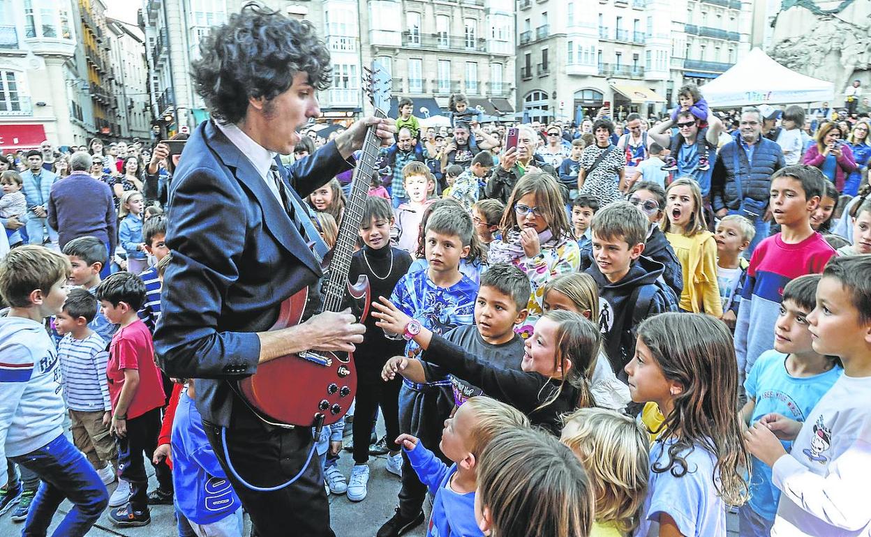 Uno de los guitarristas de Black Back Band, a pie de calle, muestra a los niños cómo se toca la guitarra. 