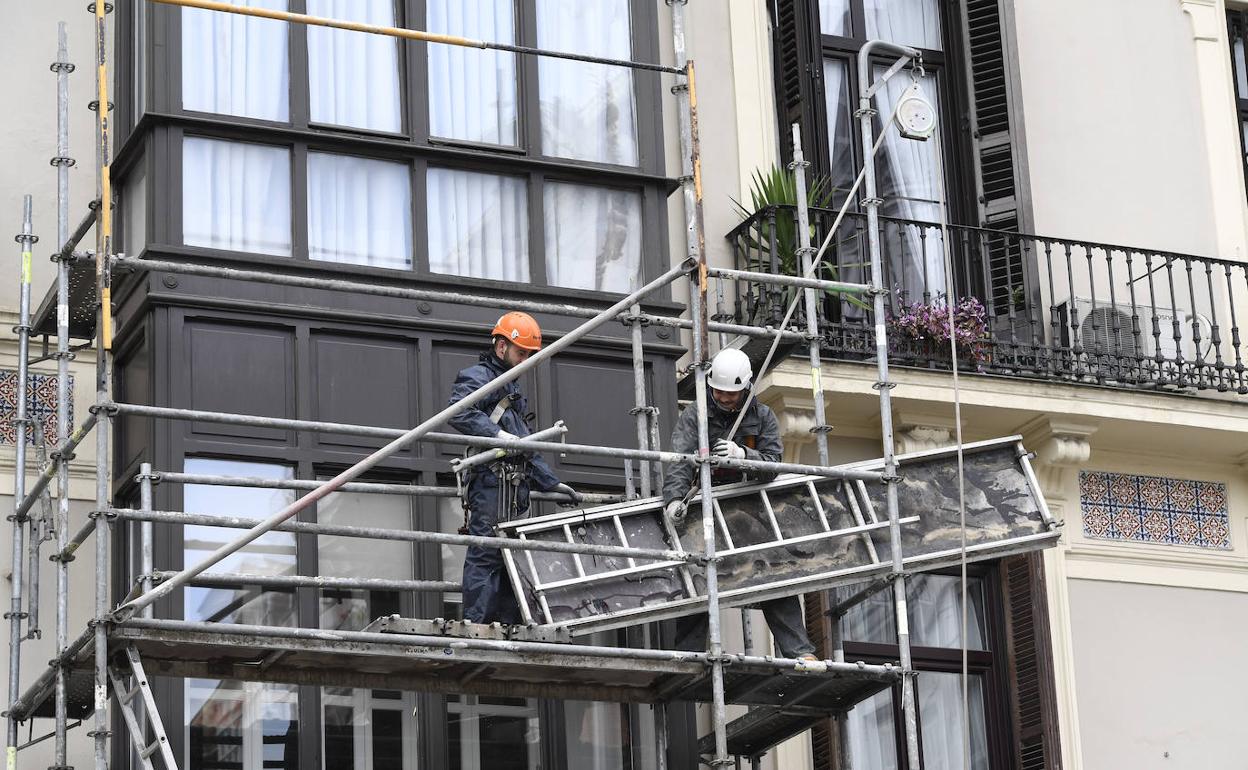 Operarios trabajando en la reforma de la fachada de un edificio en Bilbao. 