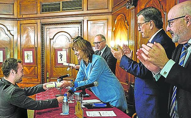 La rectora de la UPV/EHU entrega el título a uno de los nuevos periodistas ante la mirada de sus compañeros de promoción y los alumnos de la 35ª edición del Máster. 