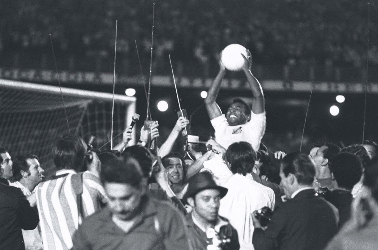 Pelé, celebra su gol número 1000 frente al número triunfal formado por balones de fútbol. 