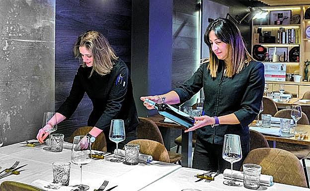 Andrea Ramírez y Ana María Sánchez revisan los detalles de una mesa en su restaurante. 