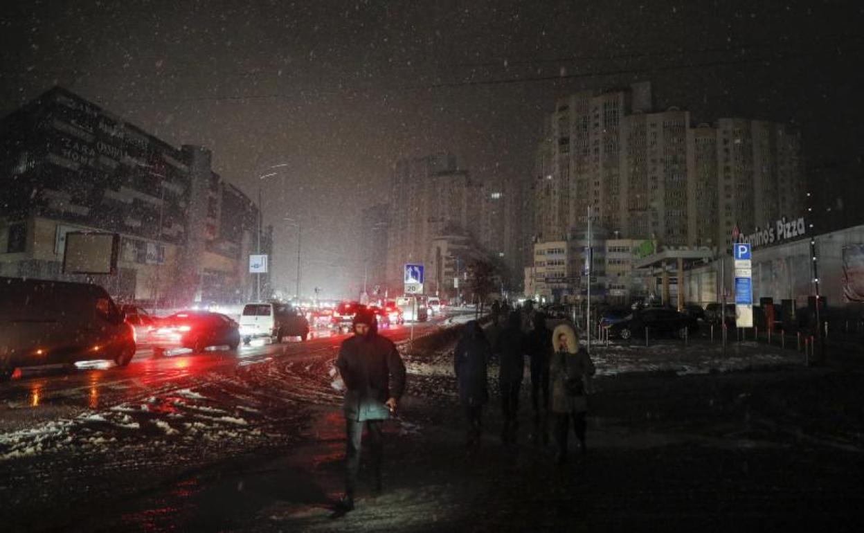 Vecinos de Kiev caminan por un barrio sin electricidad tras un ataque ruso. 