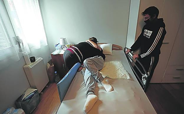 Ana Claudia abraza a su hijo, que pasa la mayor parte del día encamado, ante la mirada del padre, Eugenio, en el piso al que se han trasladado tras salir del hospital de Gorliz. 