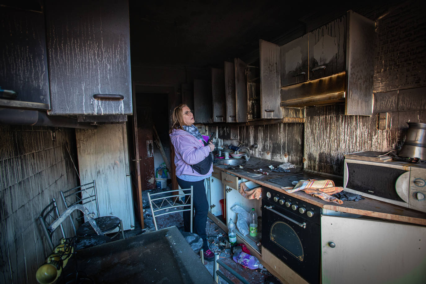Una vecina observa los daños provocados en un piso incendiado en Santutxu, por segunda vez en dos meses, el pasado 3 de enero