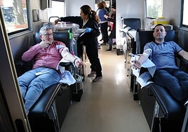 Dos personas donan plasma sanguíneo en un autobús del Banco de Sangre.