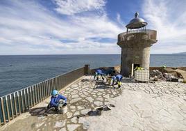 Los obreros rejuntan las piedras del nuevo pavimento de la plataforma del faro.