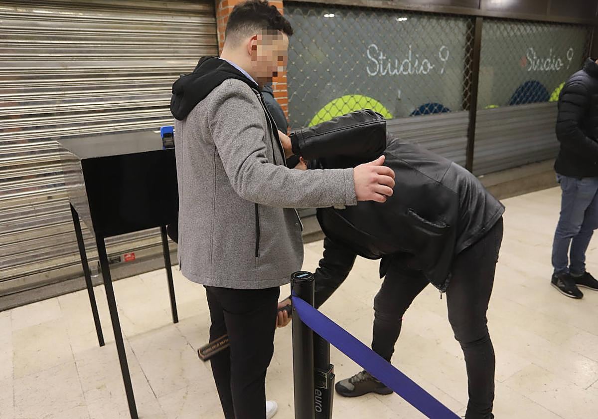 Uno de los vigilantes inspecciona con un detector de metales a un cliente.