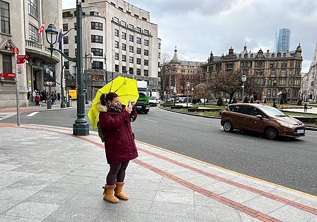 Una mujer hace una foto en la plaza de Moyua mientras cae ligeramente aguanieve.