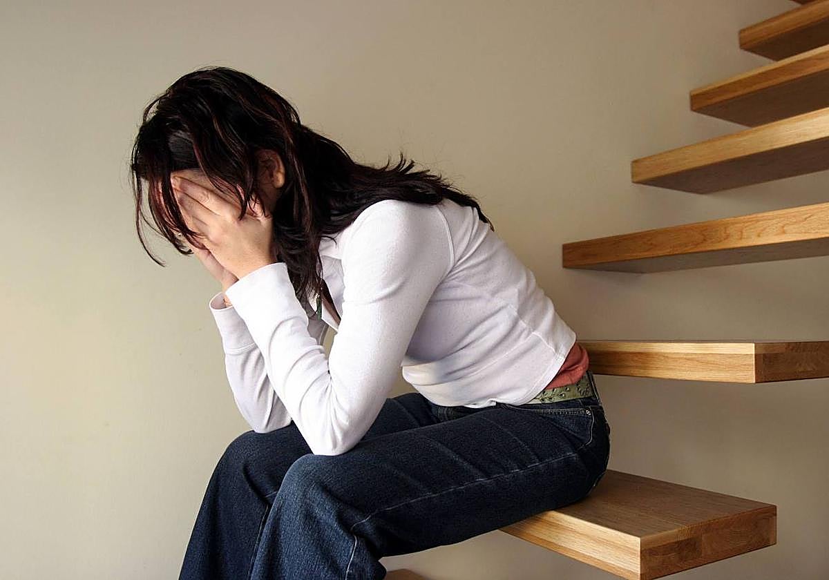 Una mujer se lleva las manos a la cabeza en medio de una crisis depresiva.