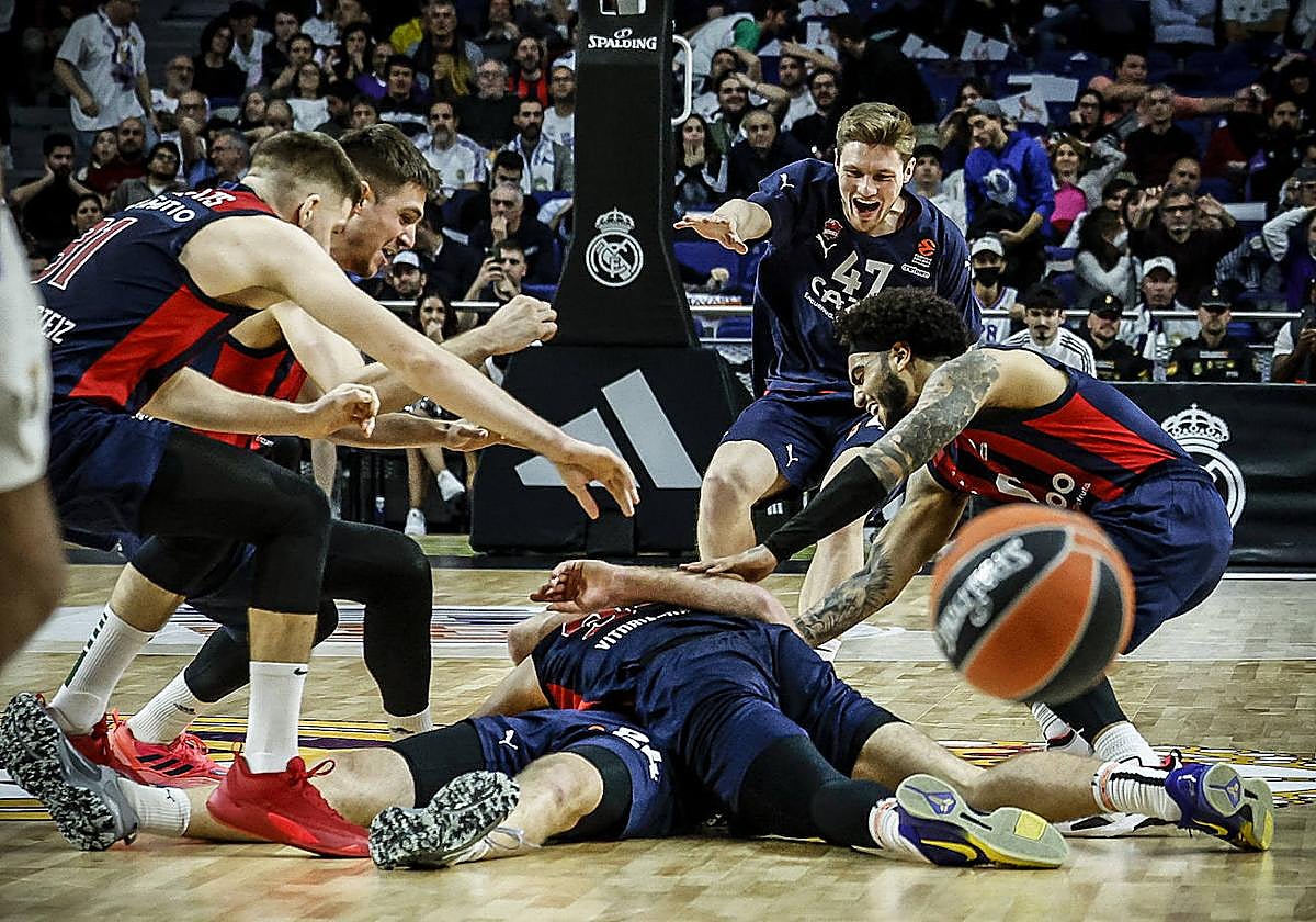 La alborozada plantilla baskonista abraza a Matt Costello, tendido sobre el parqué, después de anotar el tiro que aseguró el triunfo en Madrid.