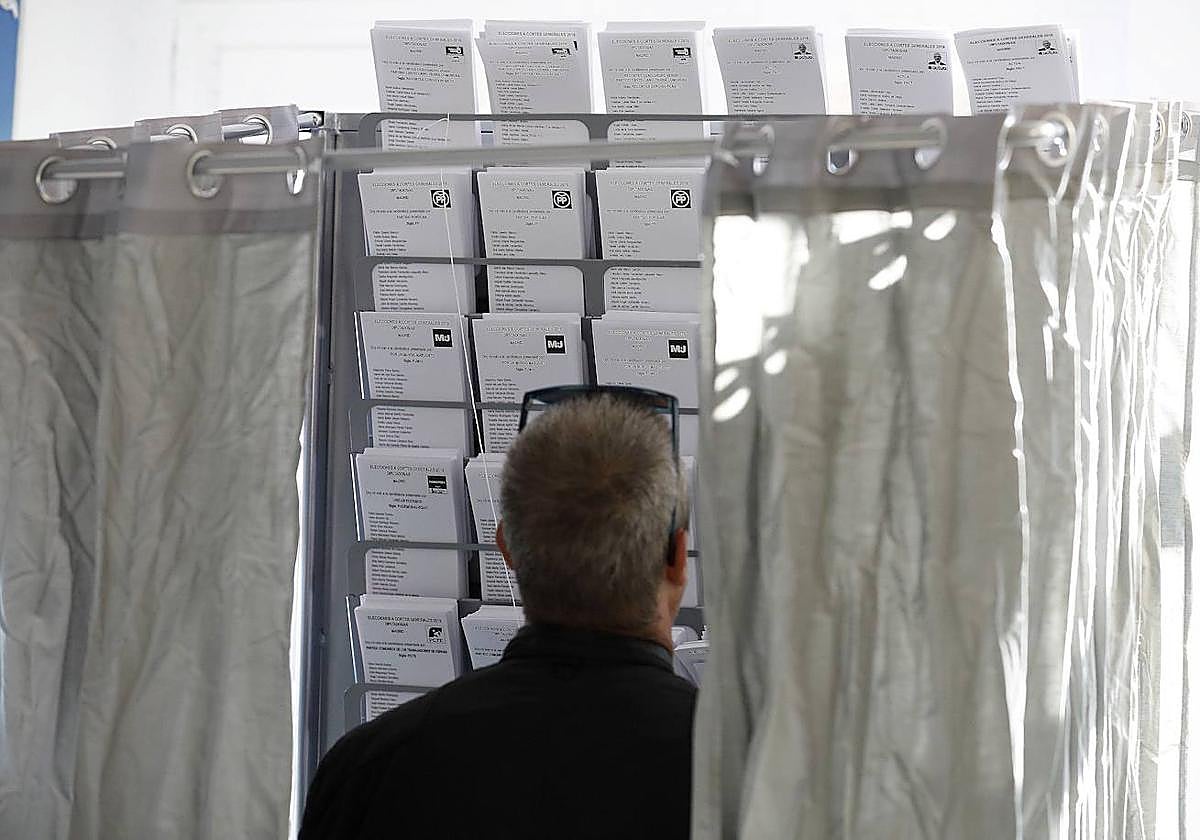 Un hombre observa las papeletas en una cabina electoral.