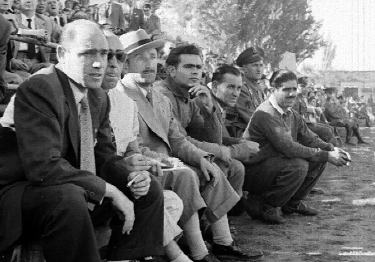 Lecube, tercero por la izquierda (con sombrero), en el banquillo del Camp d'Esports.