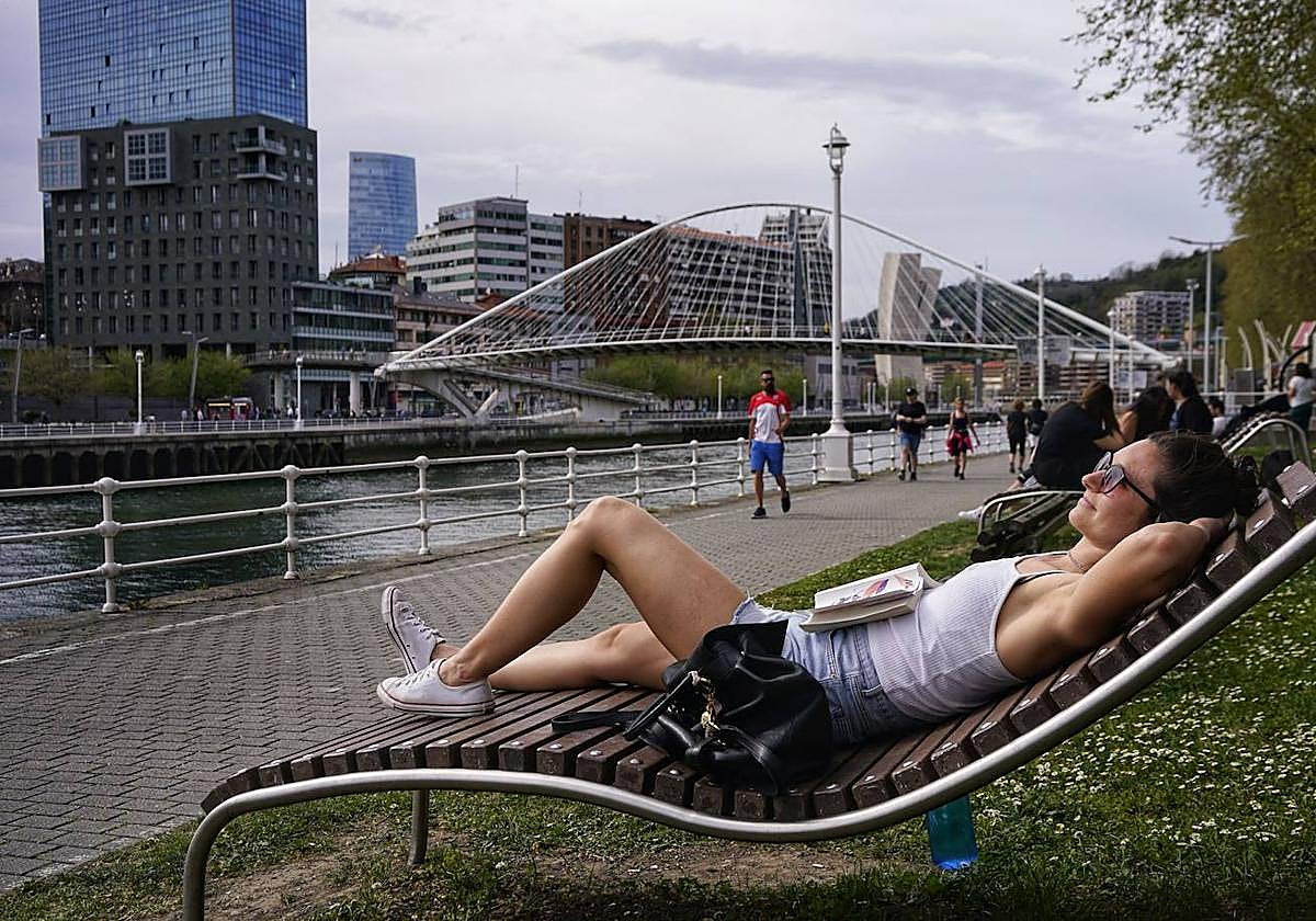 Una vecina de Bilbao toma el sol en una de las tumbonas de la ría.