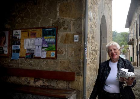 Imagen secundaria 1 - Raúl recostado en una casa de Lanestosa. Otra vecina de la villa, Pili Ranero, pasa con un bizcocho junto al panel de anuncios. José Ángel y Manuel conversan en el Bar Rosi.