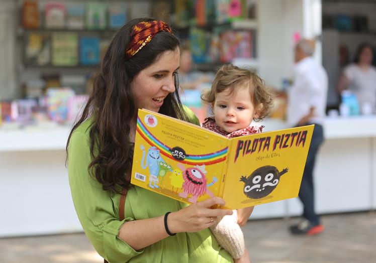 Guria Gutiérrez, enseñando a June el libro 'Pilota Piztia', de Olga de Dios, que ha comprado a su hijo mayor, Ohian, que tiene cuatro años.