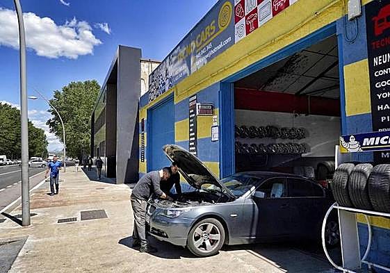 Trabajadores examinan el motor de un vehículo en el taller TecnoCars que se localiza en la calle Portal de Gamarra.