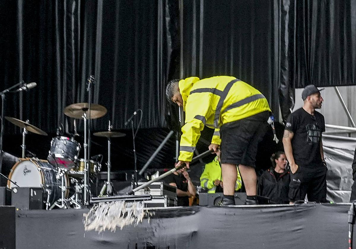 Operarios del Azkena retiran el agua acumulada sobre uno de los escenarios del recinto.