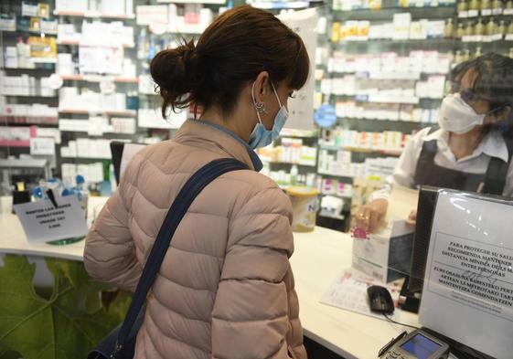 Una mujer realiza una compra en una farmacia.