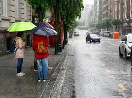 Varias personas aguardan un taxi en la parada de Moyua, en plena tormenta este pasado domingo.