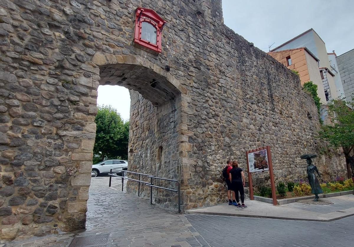 Dos turistas madrileños consultan la información del panel correspondiente a Sanjuanportale, la única puerta de la muralla medieval de Bermeo que se mantiene en pie.