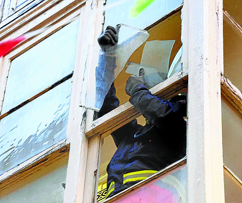 Un bombero revisa los cristales en una vivienda.